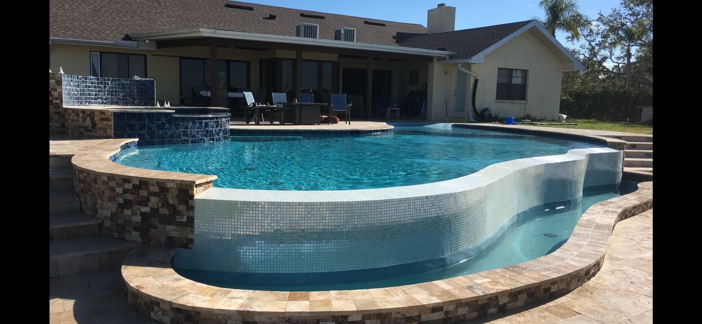 A large swimming pool is in the backyard of a house.