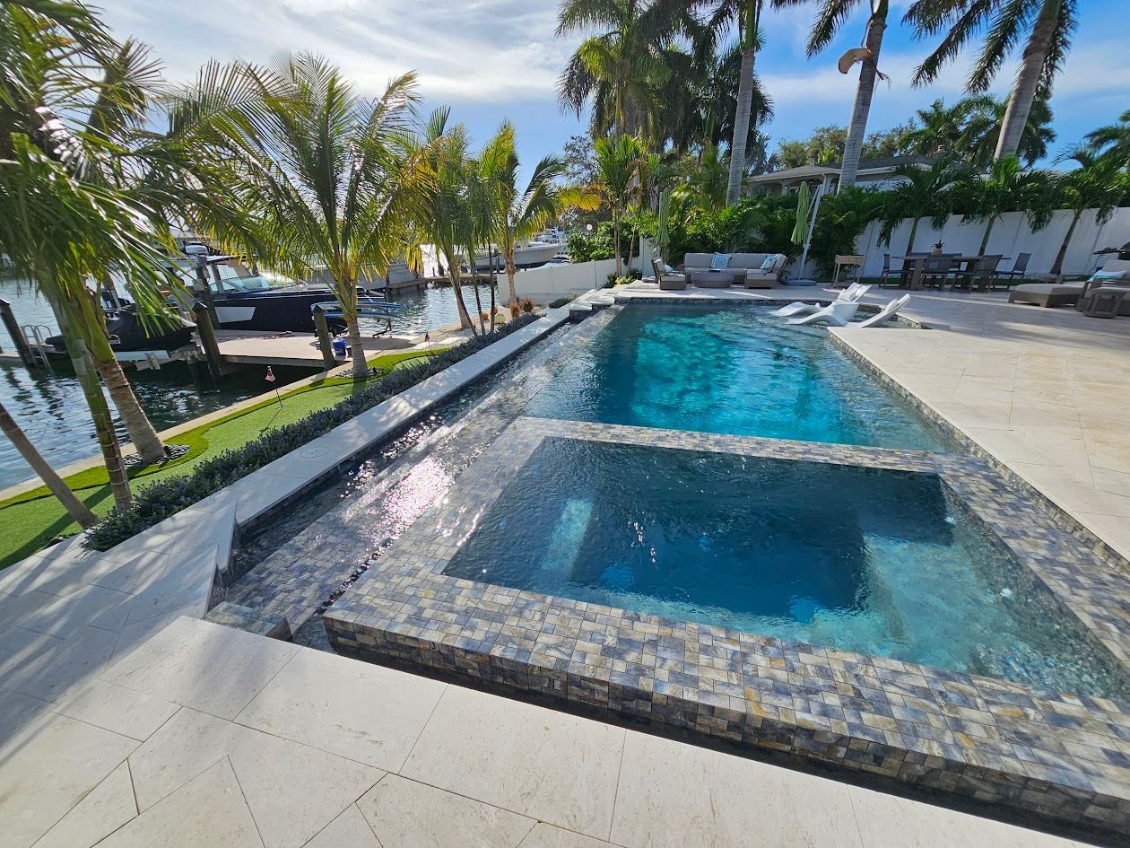 A large swimming pool with a hot tub in the middle surrounded by palm trees.