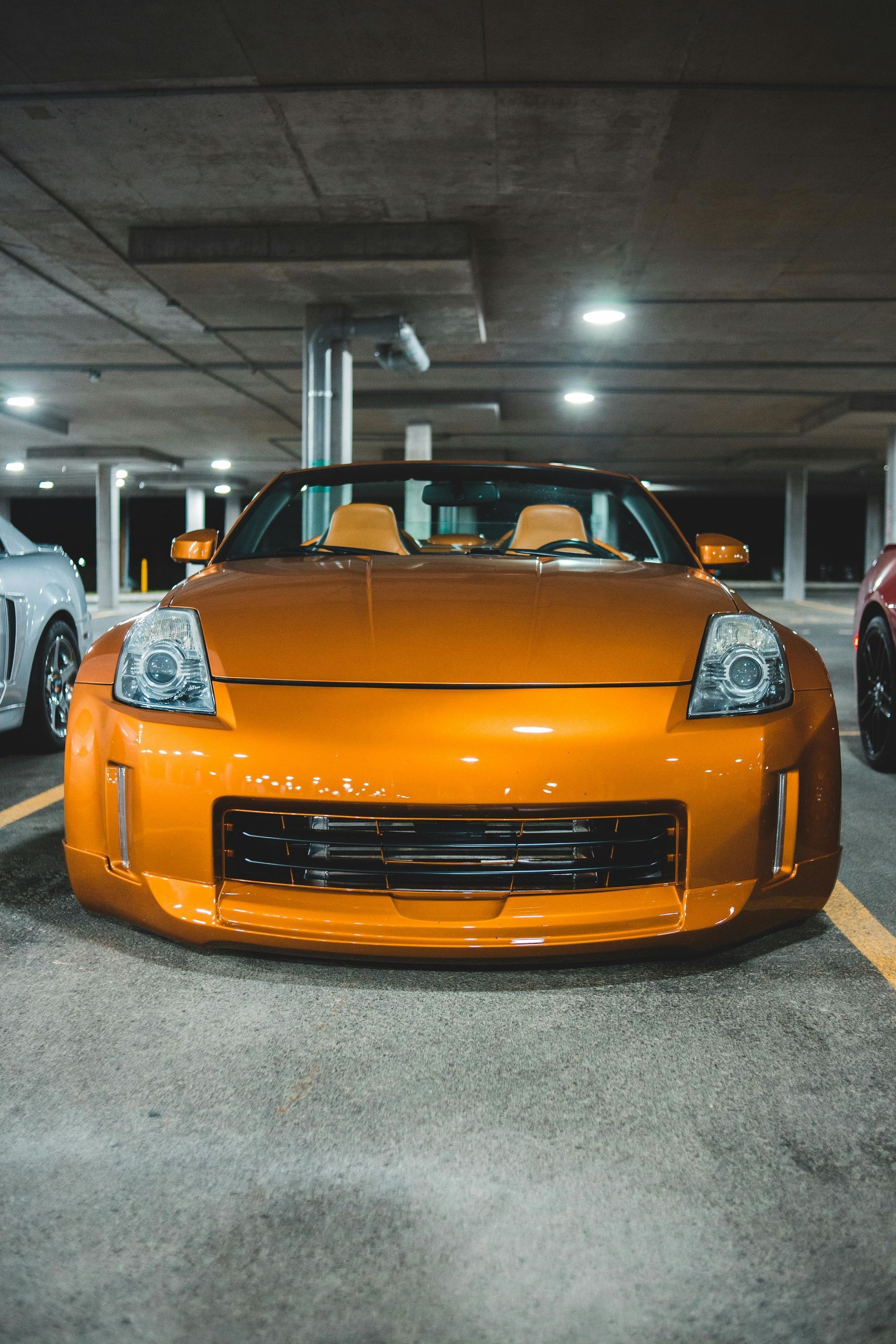 An orange sports car is parked in a parking garage.