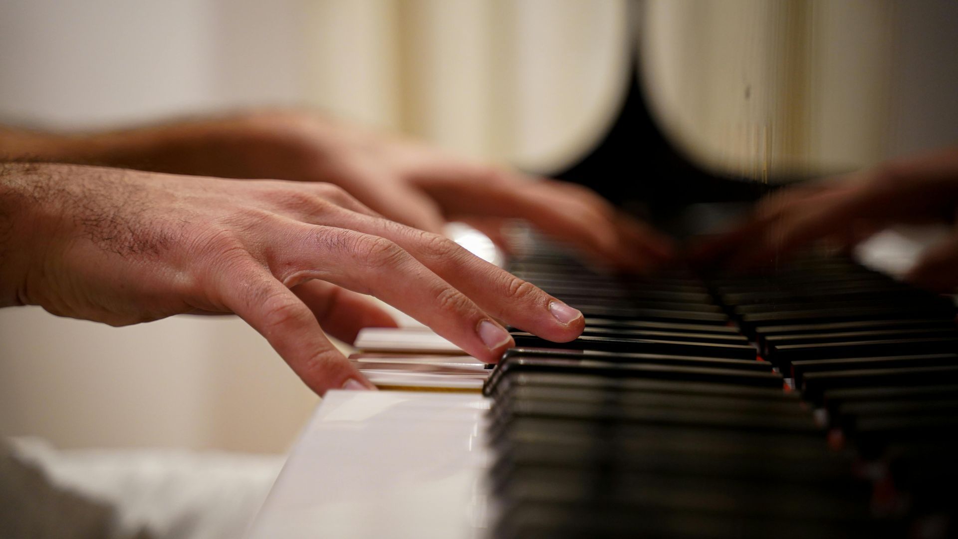 Hands playing piano keys; focus on the fingers and instrument.