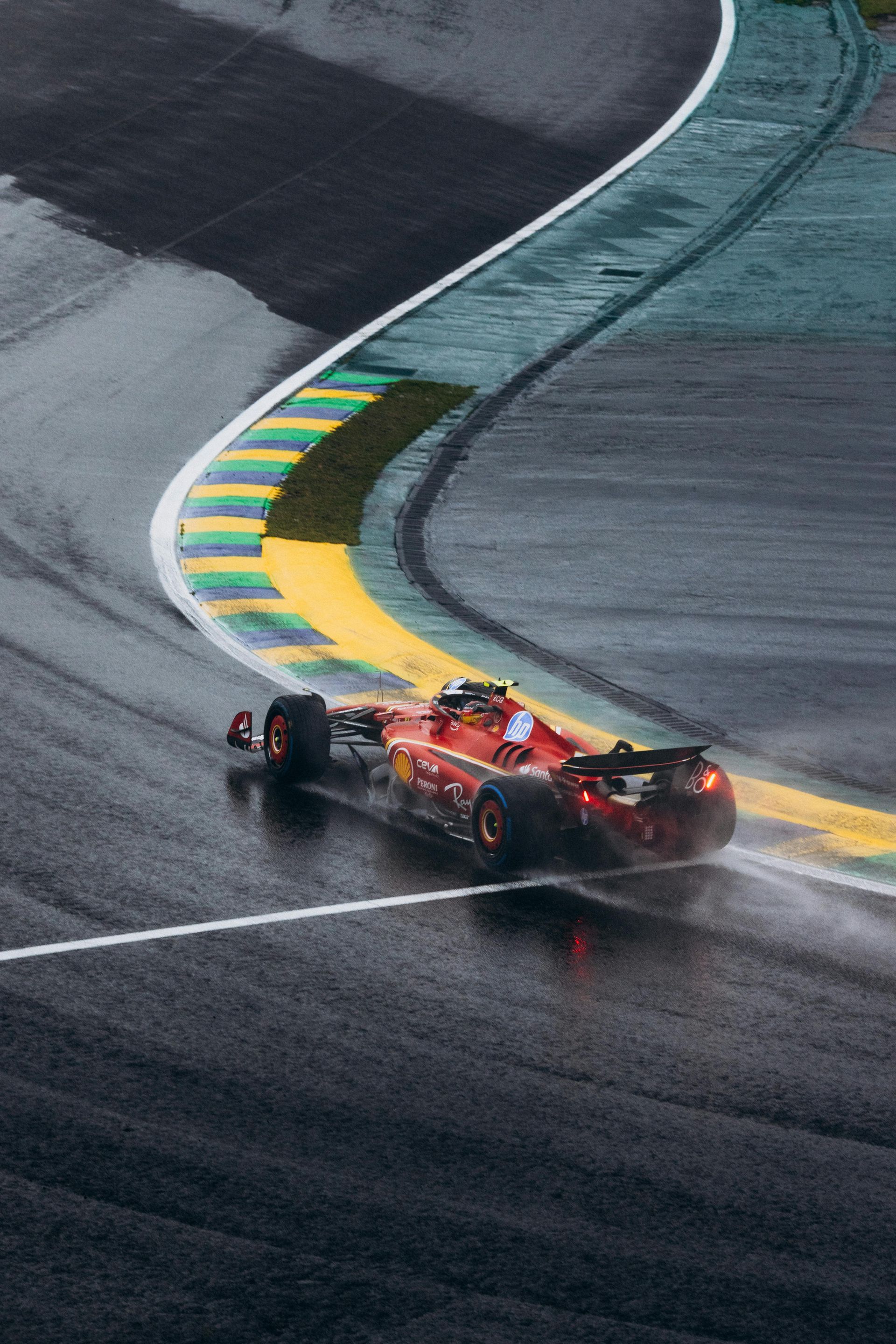Formula 1 car speeds around a wet track, spray trailing behind.
