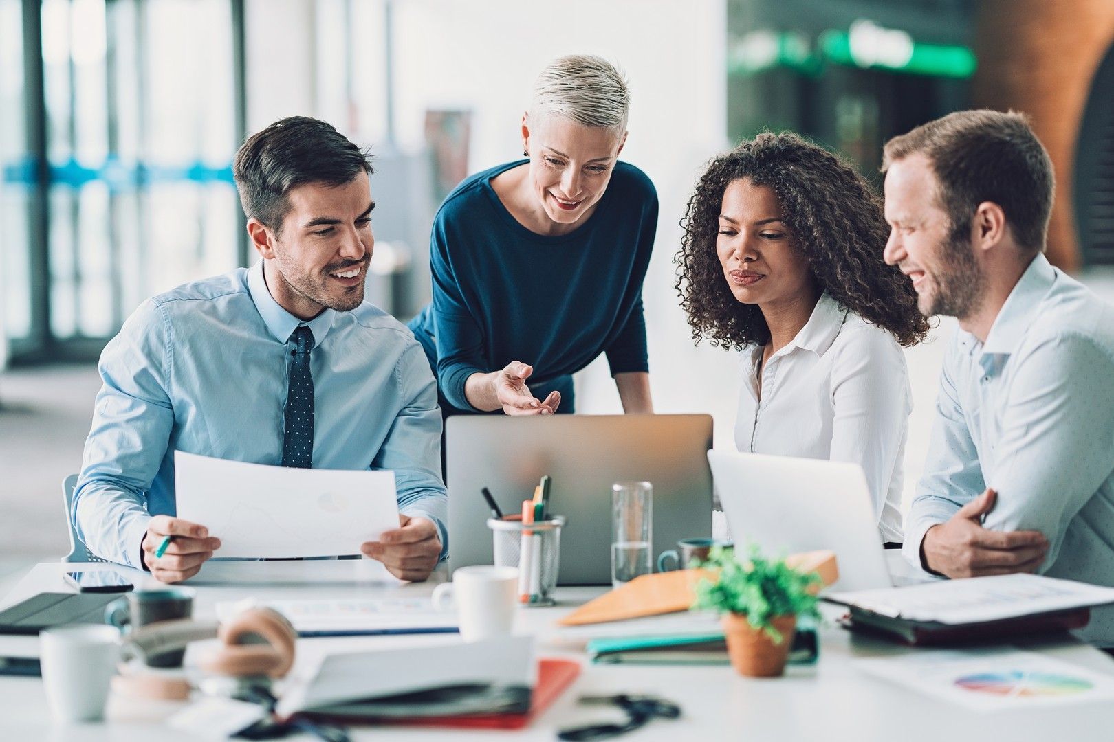 Un gruppo di uomini d'affari è seduto attorno a un tavolo e guarda un computer portatile.