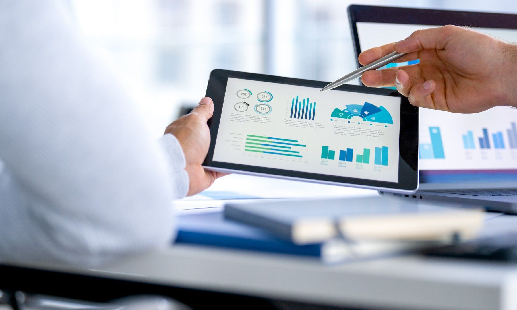Una persona tiene in mano un tablet con dei grafici e lo indica.