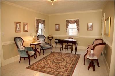 A living room with a rug and chairs and a desk