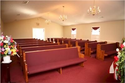 An empty church with red benches and a chandelier