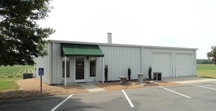 A large white building with a green awning is sitting in a parking lot.