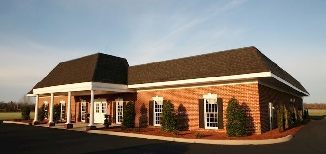 A large brick building with a brown roof and white shutters