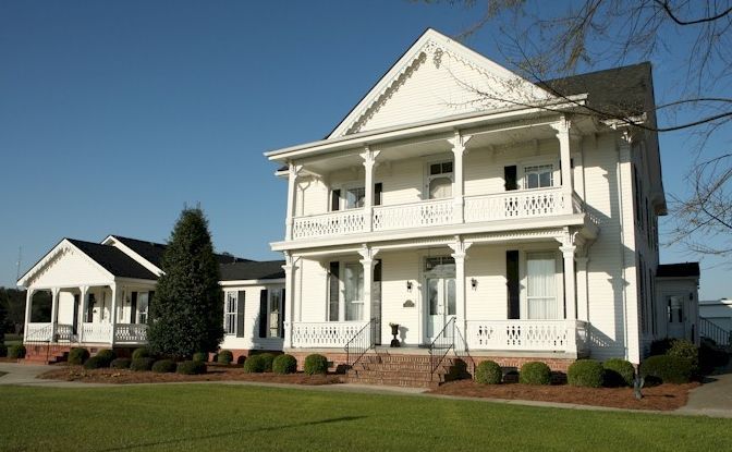 A large white house with a large porch on a sunny day