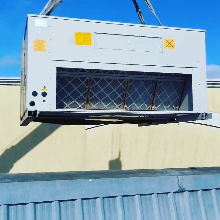 Una gran caja blanca con una x amarilla está siendo levantada por una grúa.