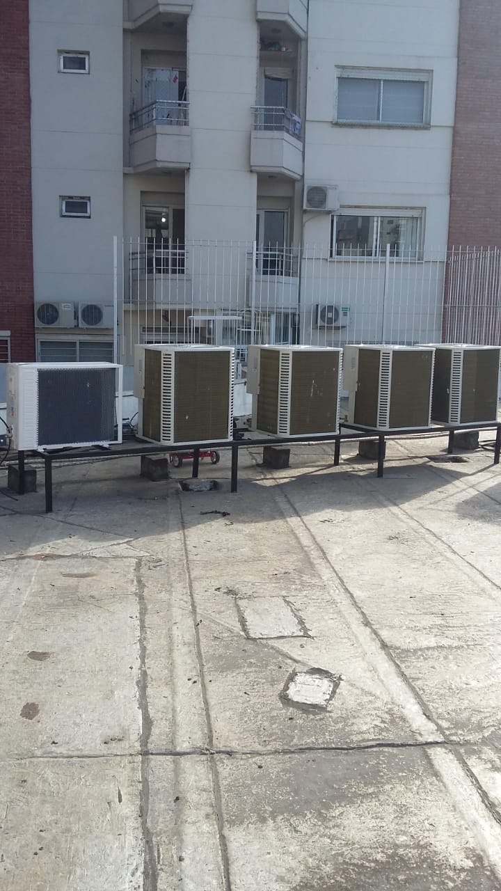Una fila de aparatos de aire acondicionado están colocados en el techo de un edificio.