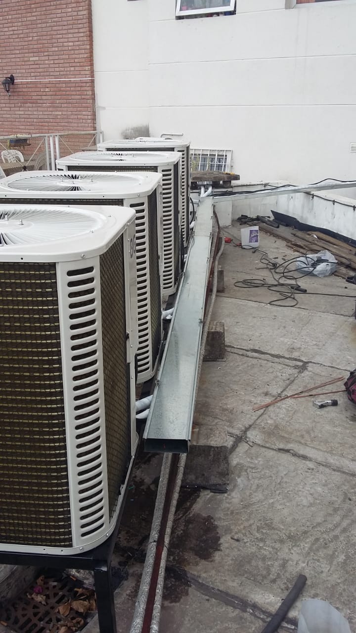 Una fila de aparatos de aire acondicionado están colocados en el costado de un edificio.