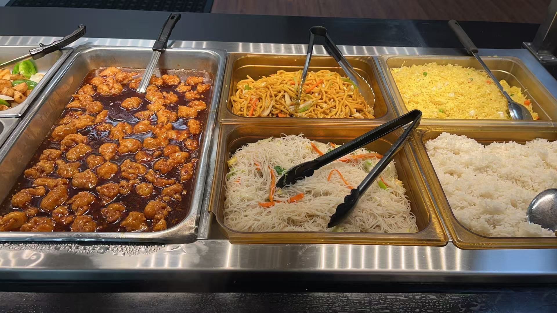 Person grilling meat at a Japanese barbecue, using tongs. Raw meat and side dishes visible. Person grilling meat at a Japanese barbecue, using tongs. Raw meat and side dishes visible.