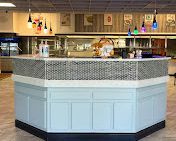 A light blue and mosaic tile counter in a diner. Hanging pendant lights in the background.