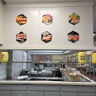 Sushi restaurant interior: counter with open kitchen view, sushi art on the wall, and Japanese lanterns.