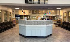 Reception area with a blue and white counter, waiting chairs, and light-colored floors.