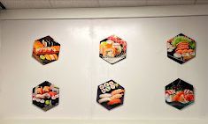 Six hexagonal sushi photos mounted on a white wall.