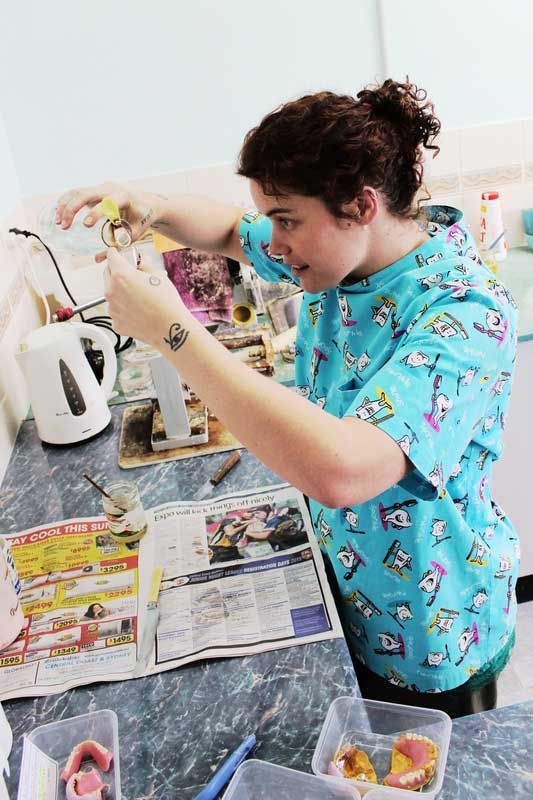 Technician working on new dentures holding a measure cup — Dentures in Toukley, NSW