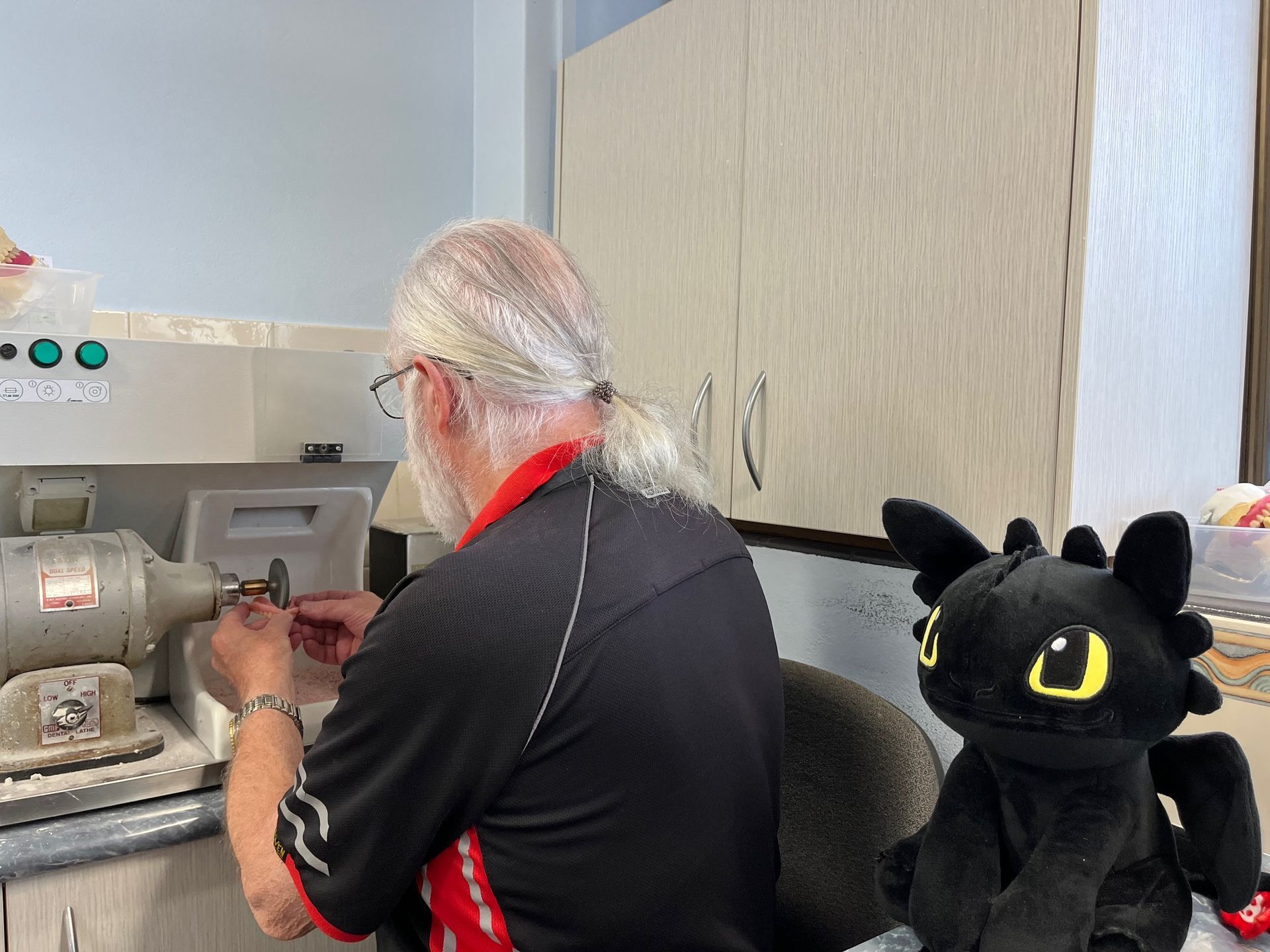 Technician working on new dentures holding a measure cup — Dentures in Toukley, NSW
