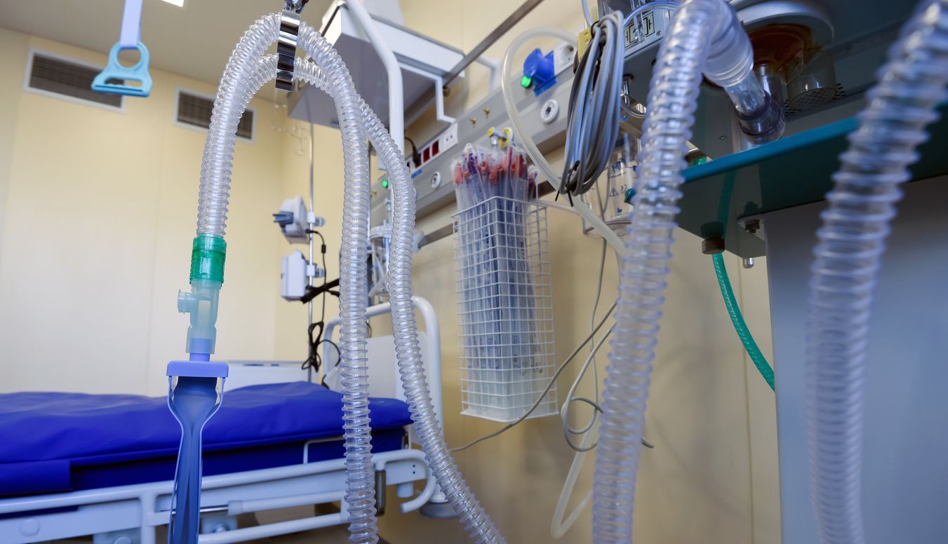 A hospital room with a bed and a bunch of medical tubing hanging from the ceiling.