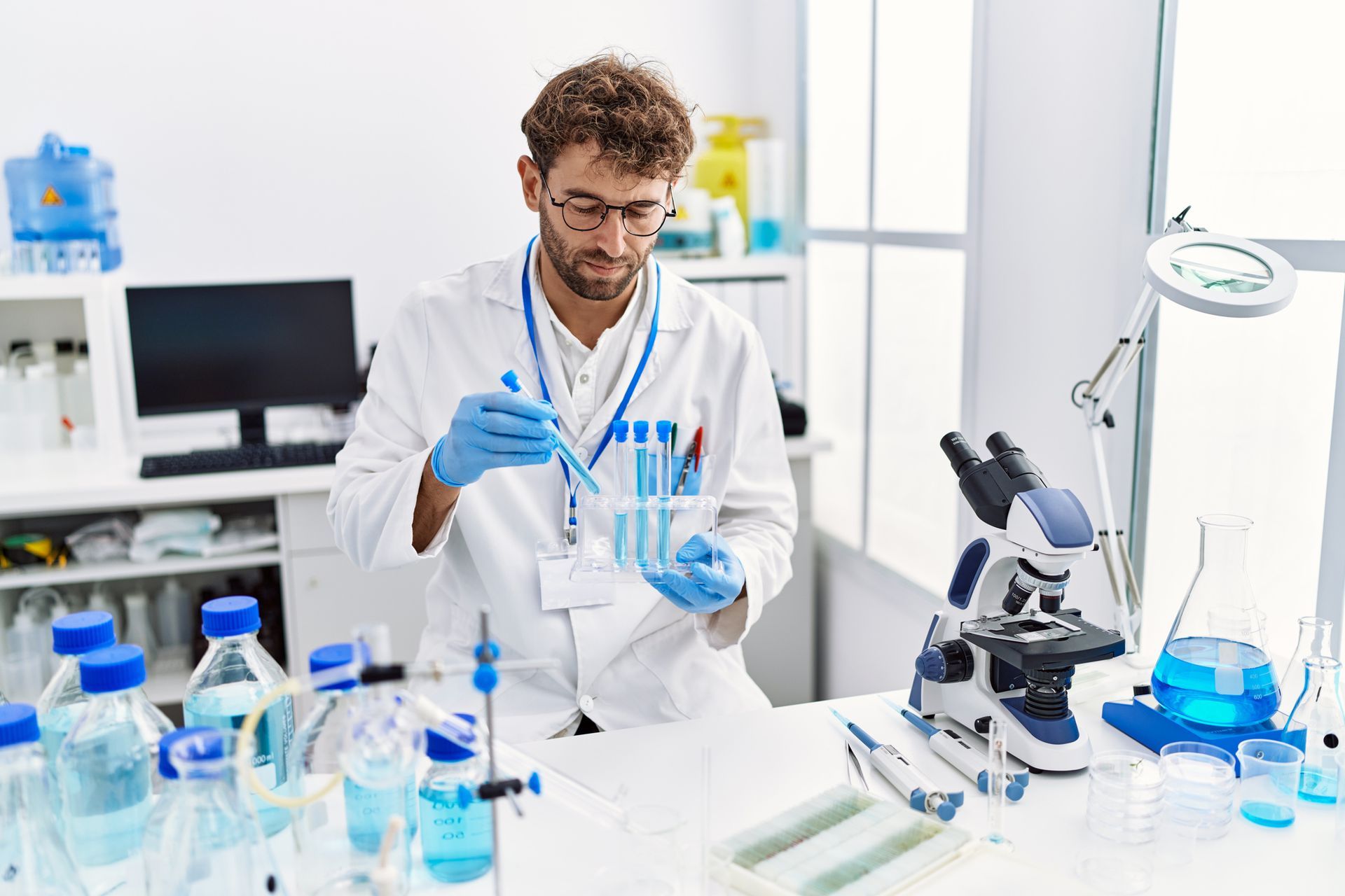 A doctor is working in a laboratory with a pipette and a microscope.