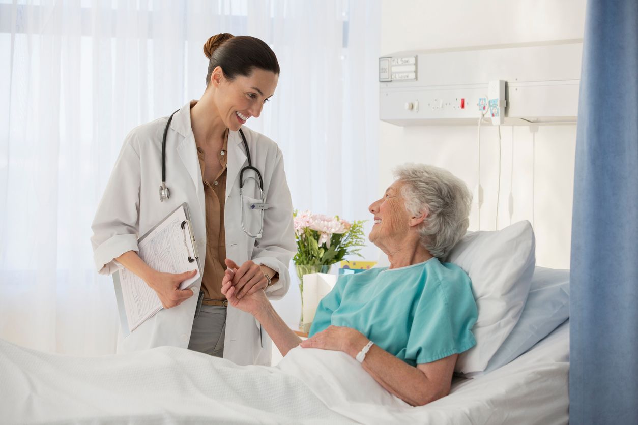 A doctor is talking to an elderly woman in a hospital bed.