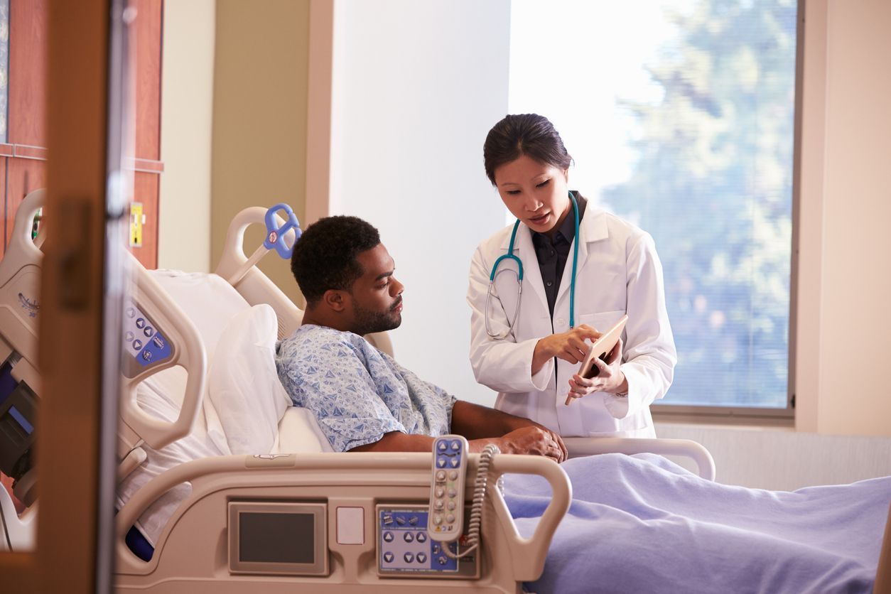 A doctor is talking to a patient in a hospital bed.