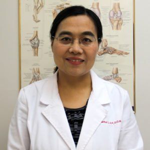 A woman in a white lab coat is smiling for the camera