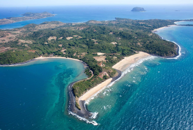 Aerial view of a tropical island with lush greenery, sandy beaches, and clear blue ocean waters.