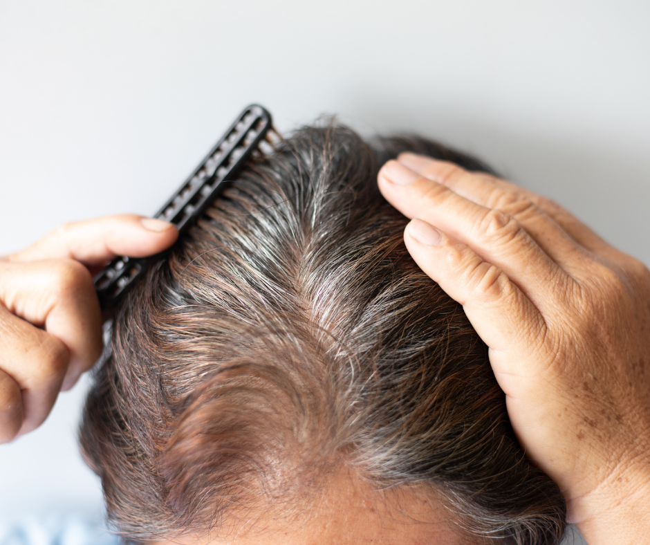 A woman is sitting in a chair holding her glasses and rubbing her forehead.