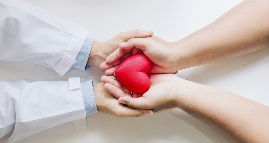 A doctor and a patient are holding a red heart in their hands.