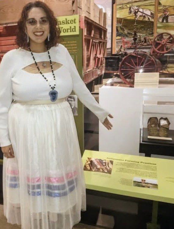 Melissa beside a museum exhibit on Indigenous farming practices