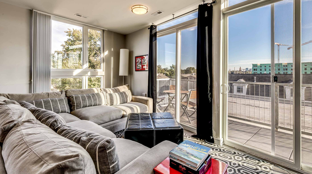The View on High Apartment Living Room with Floor to Ceiling Windows and Spacious Balcony.