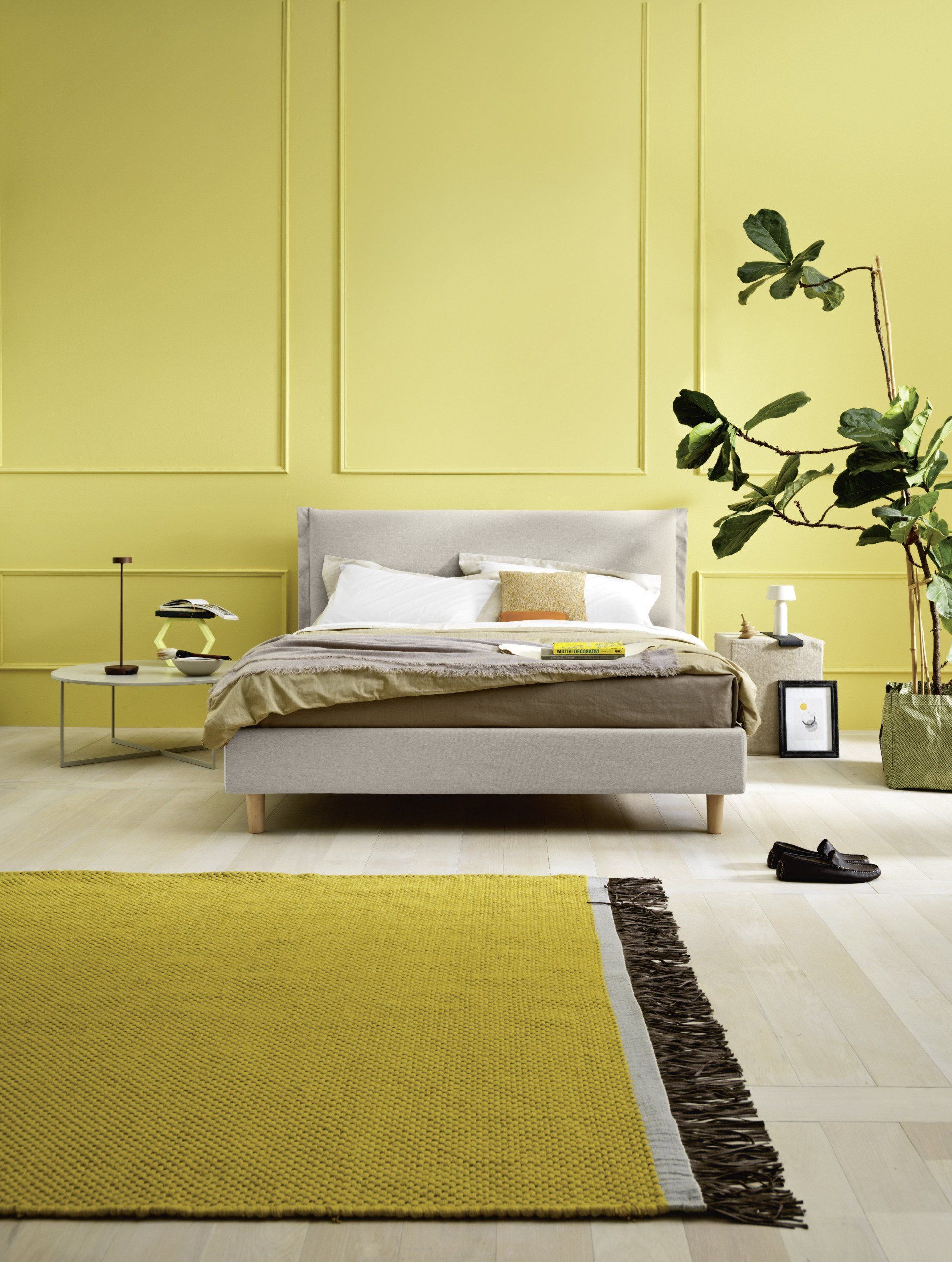 Camera da letto con letto, pareti gialle e tappeto coordinato.