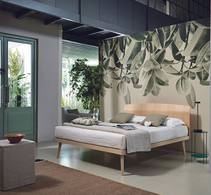 Camera da letto con letto in legno, carta da parati botanica e porta verde.