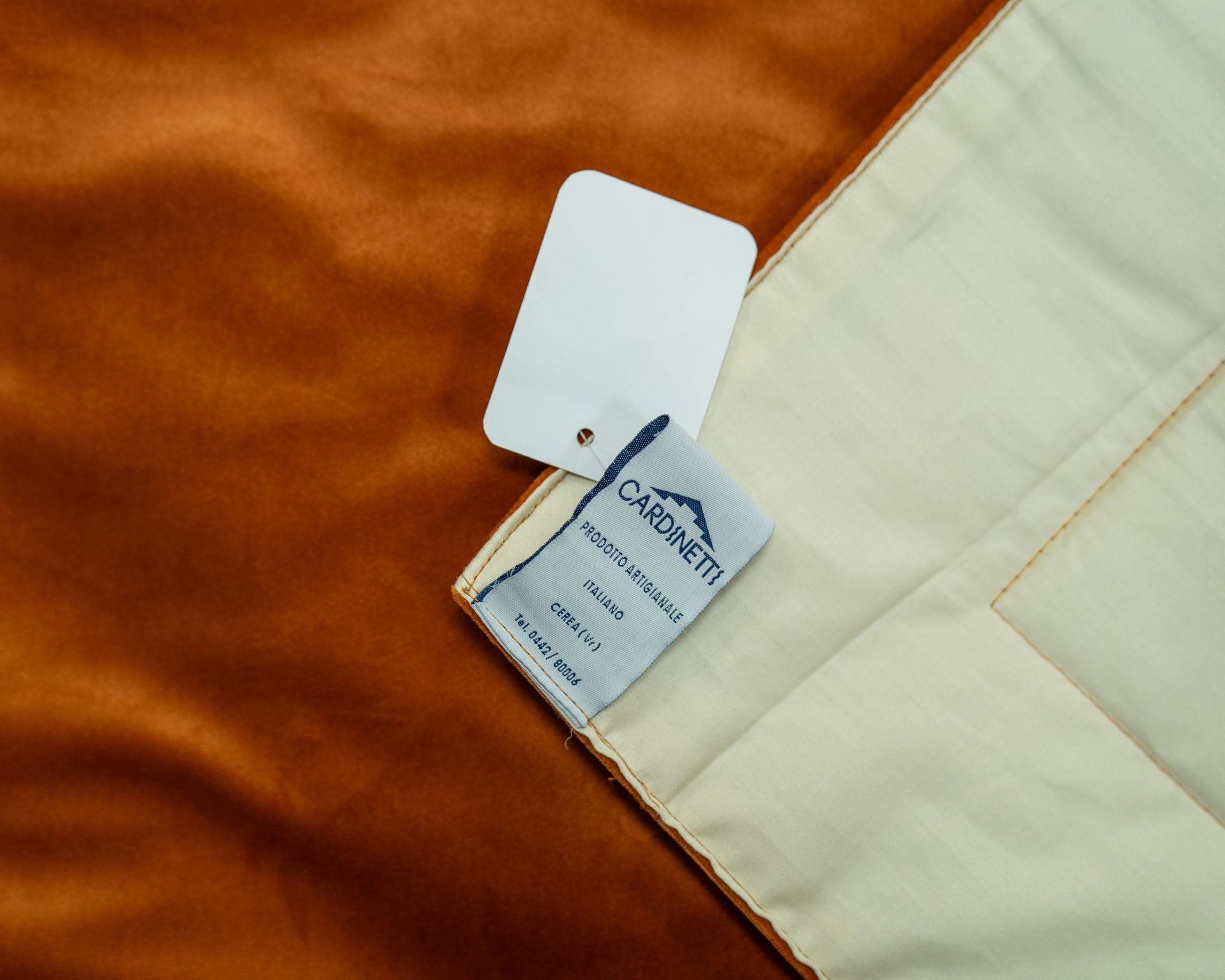 Tessuto in velluto arancione con etichetta e cartellino bianchi di Cardinetti.