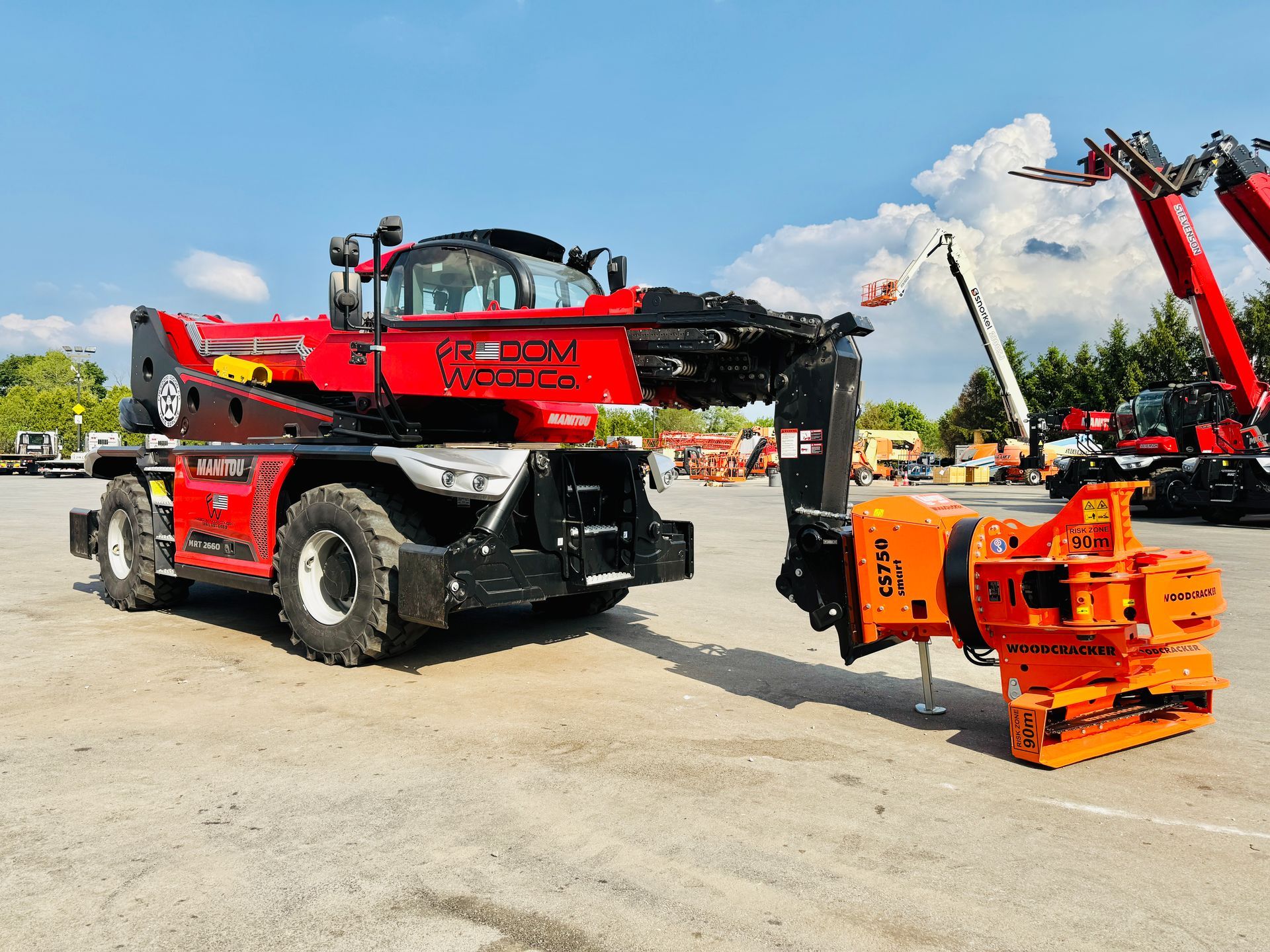 Red telehandler with an orange crusher attachment outdoors.