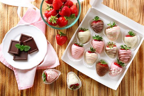 fresh strawberries in a bowl and chocolate-coated ones in a box