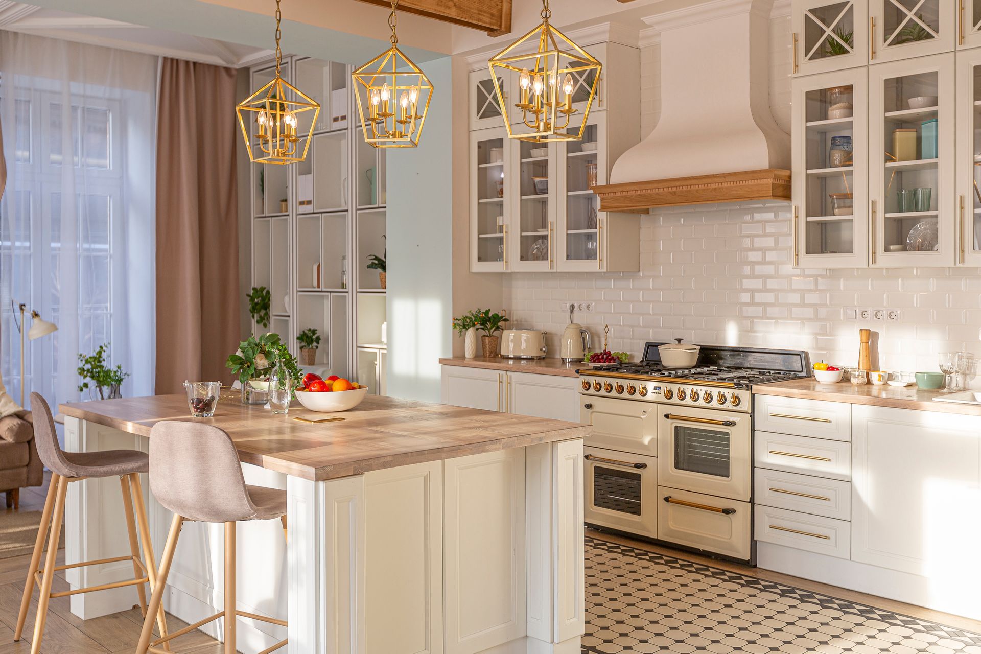 A bright kitchen with a white island, gold lights, and a cream stove. Beige tile floor.