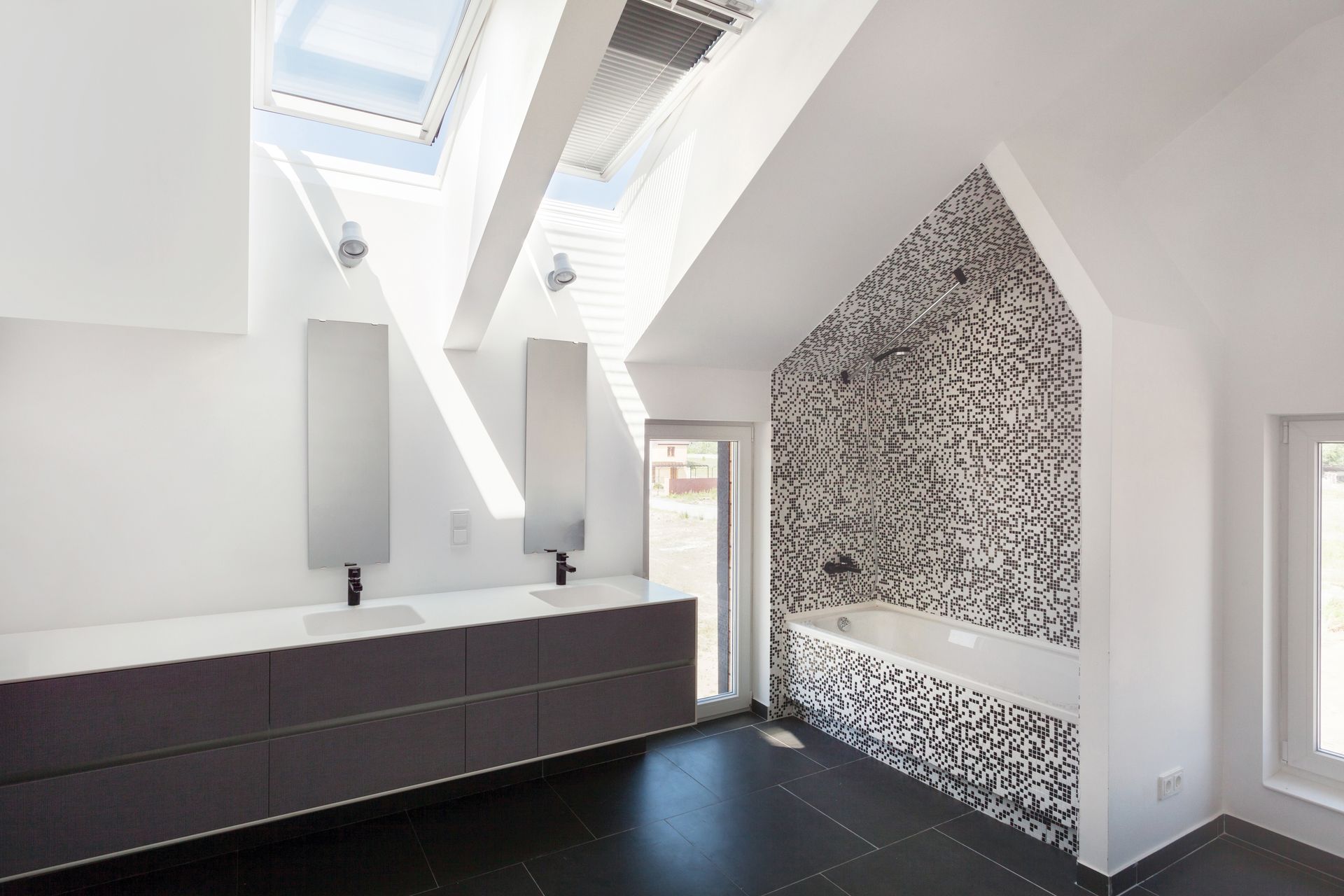 A bathroom with two sinks , a bathtub and a skylight.