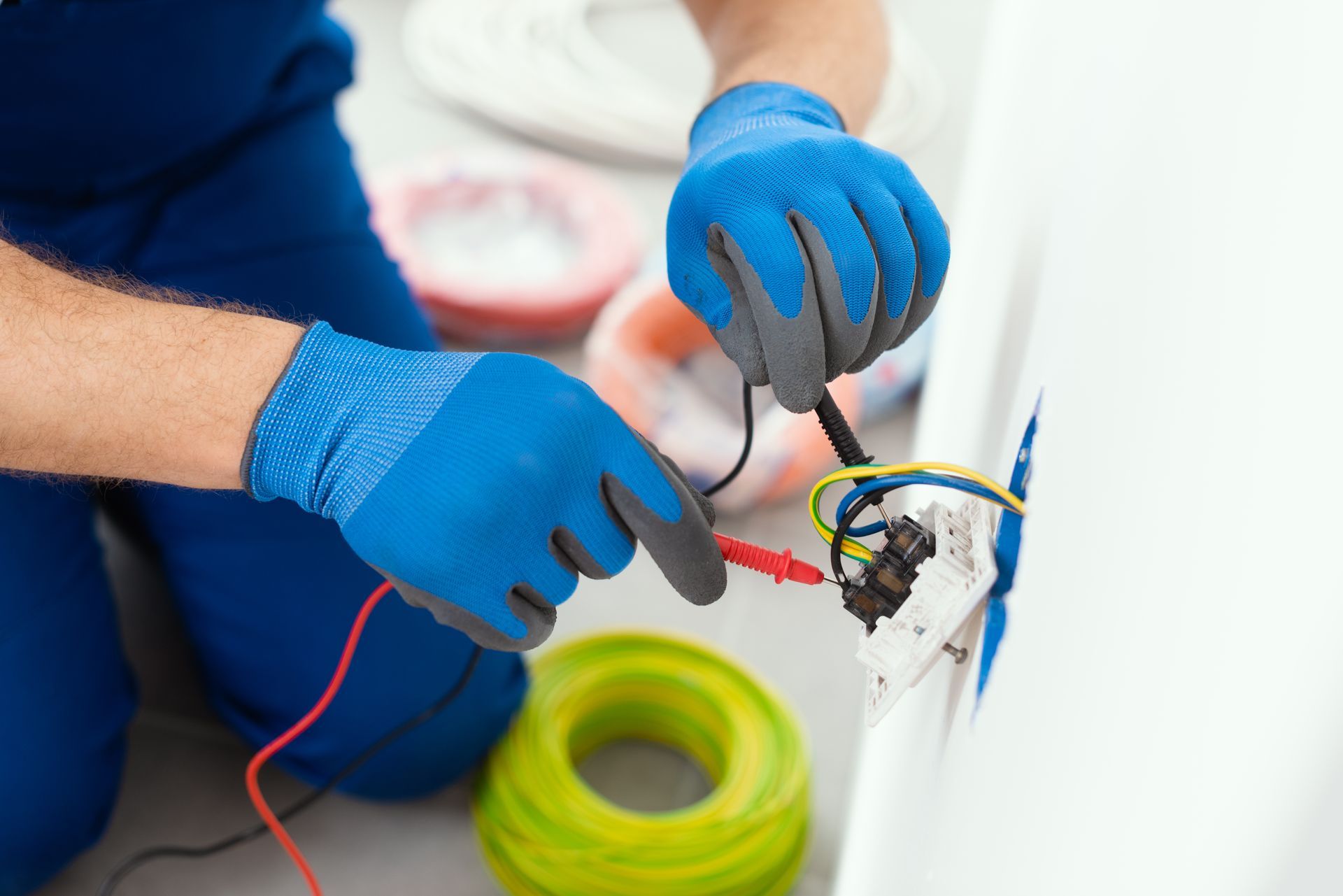 A man wearing blue gloves is working on an electrical outlet.