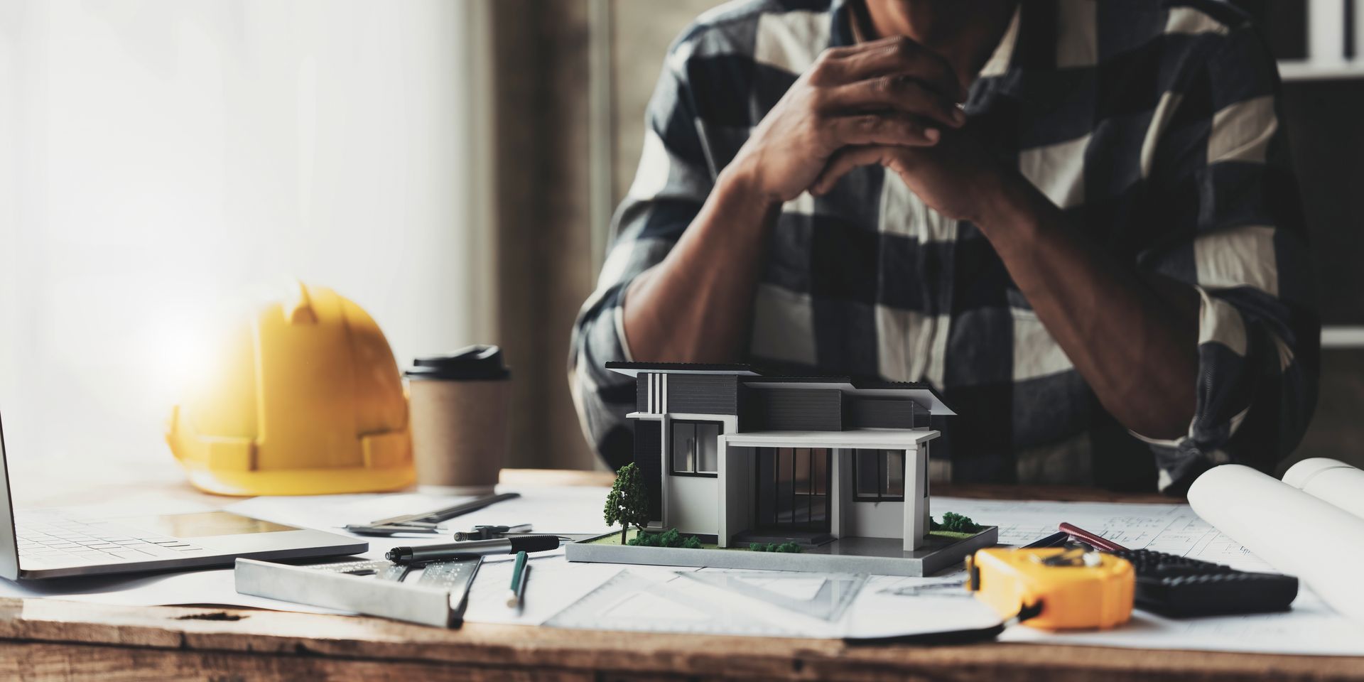 A man is sitting at a table with a model of a house on it.