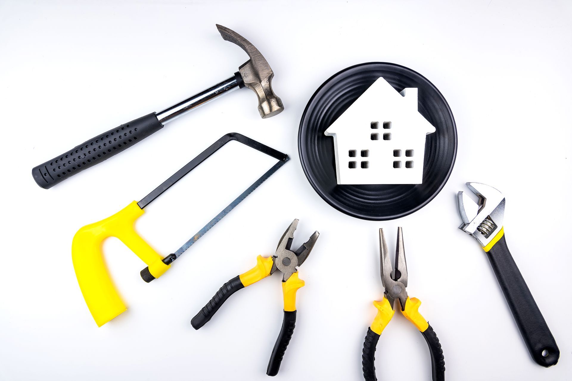 A hammer , saw , pliers , wrench and a plate with a house on it