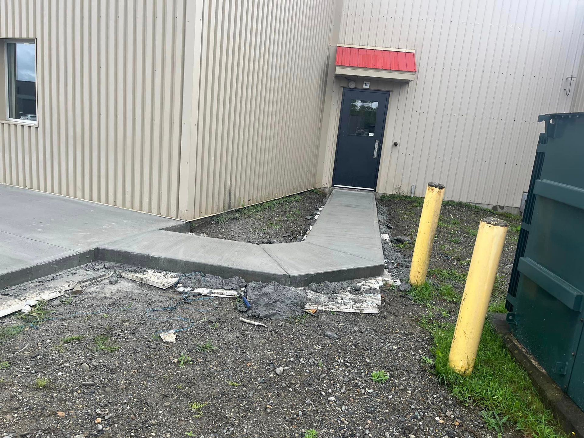 Il y a une passerelle en béton menant à la porte d'un bâtiment.