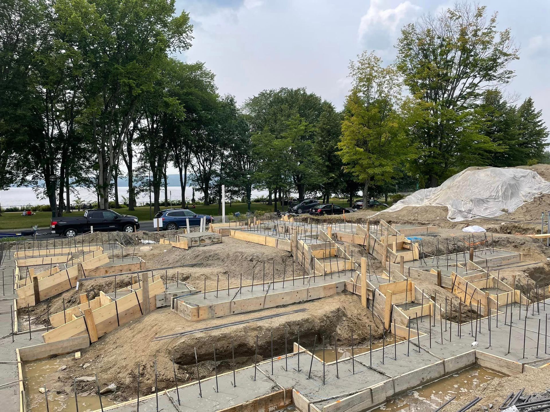 Un chantier avec beaucoup de fondations en béton et des arbres en arrière-plan.