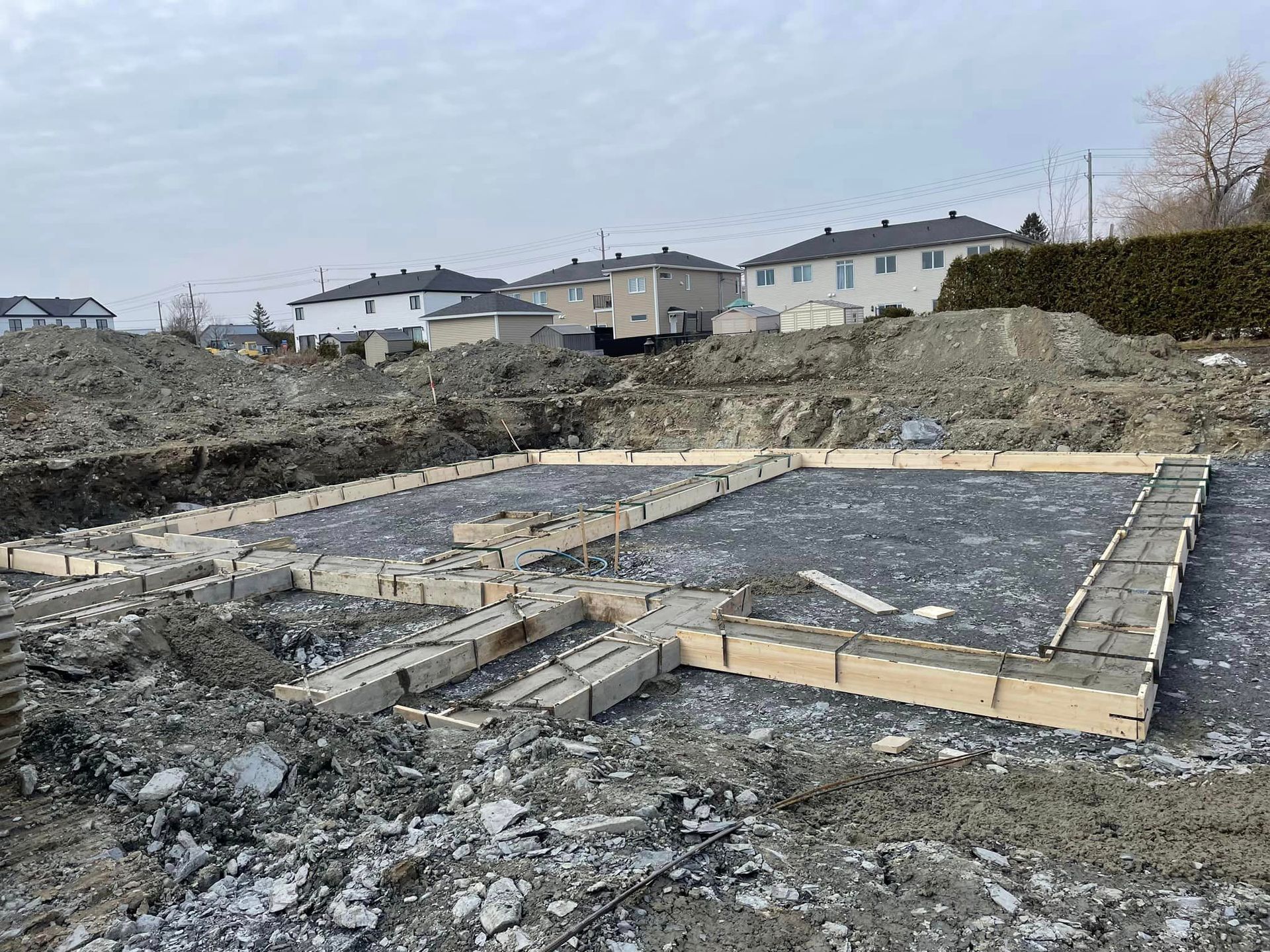 Un chantier avec beaucoup de terre et des maisons en arrière-plan.