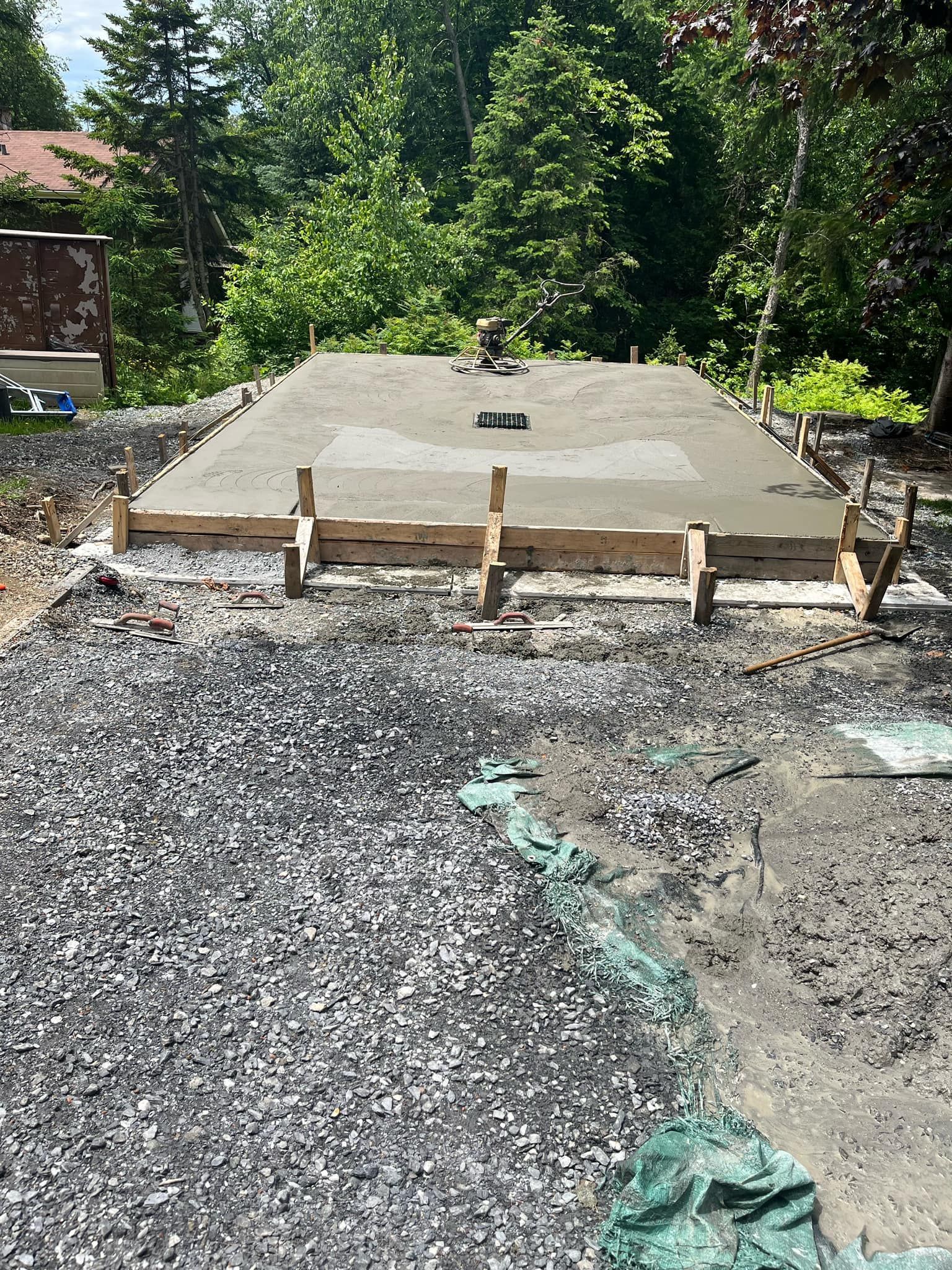 Une dalle de béton est en cours de construction sur une route de gravier.