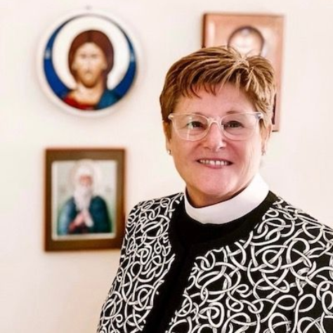 Portrait of a smiling woman in glasses before framed religious icons