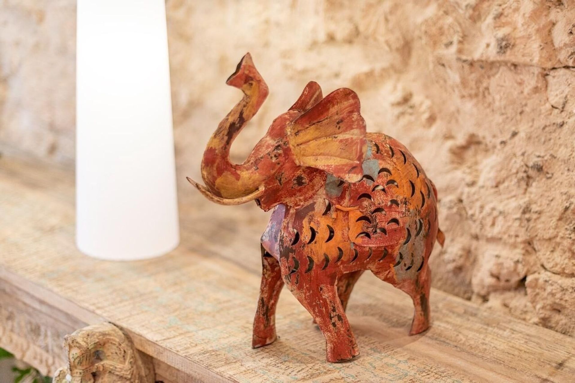 Una estatua de un elefante está sentada en una mesa de madera al lado de un candelabro.