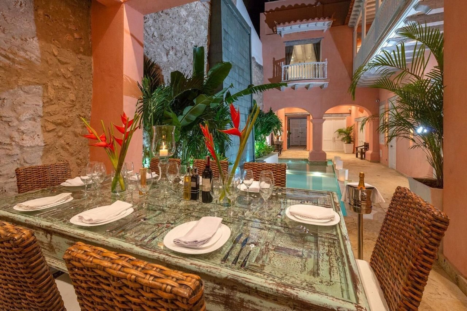 Una mesa de comedor con platos y vasos frente a una piscina.