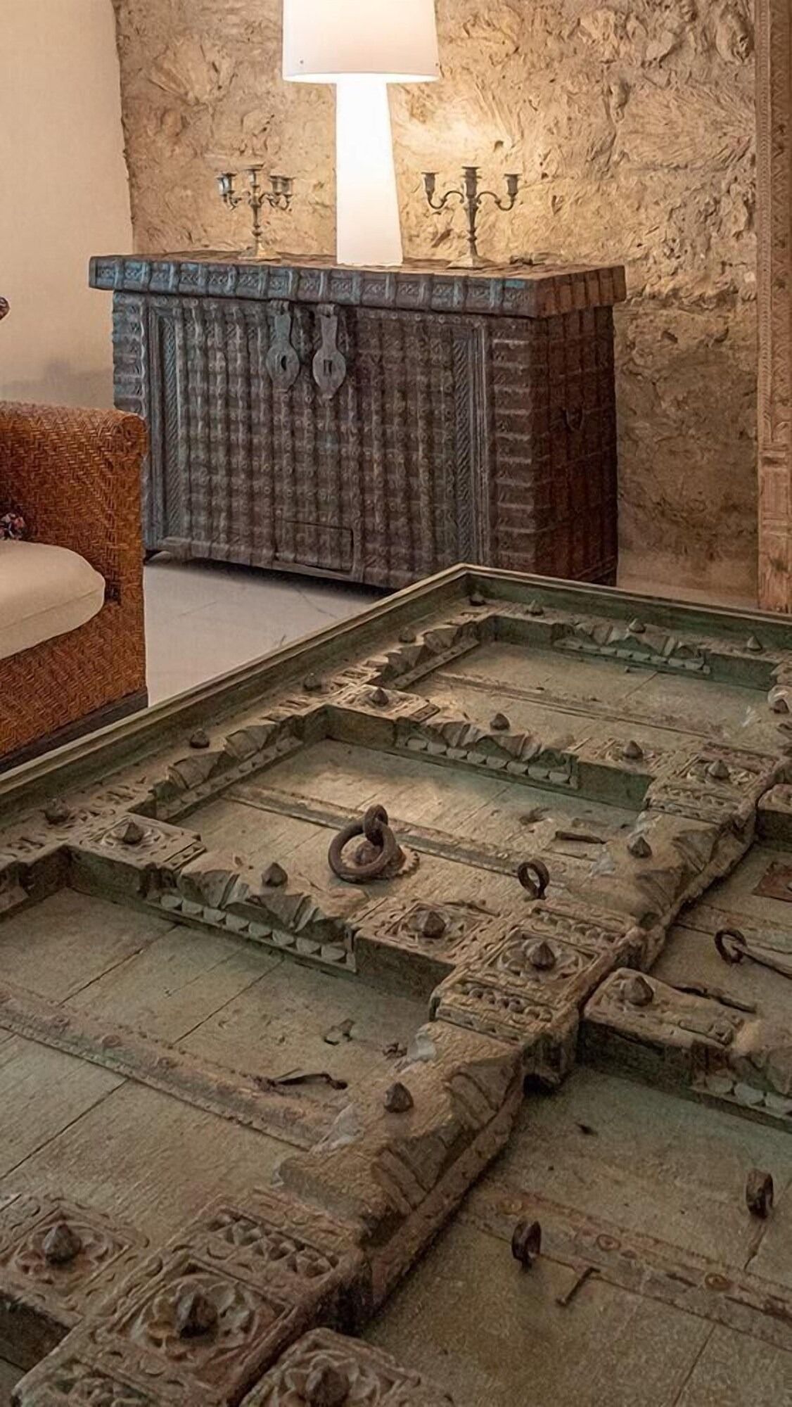 Una sala de estar con un sofá, una mesa y una lámpara. Hay un gran trozo de madera en el suelo.